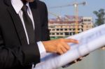 A Young Businessman Holds And Points To A Blueprint Of A Buildin Stock Photo