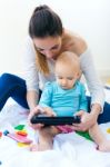 Mother And Baby Girl Using Digital Tablet At Home Stock Photo