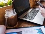 Coffee Cup  On A Table With Laptob And Graph Finance Diagram In Stock Photo