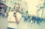 Young Man With Cell Phone Walking In City Stock Photo