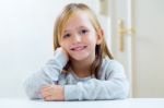 Beautiful Blonde Child Sitting At A Table In Kitchen Stock Photo