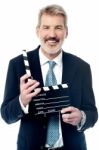 Smiling Man Showing A Clapperboard To The Camera Stock Photo