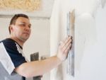 Man Worker Putting Plaster On The Wall Stock Photo