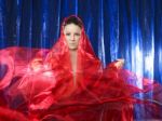 Mystic And Beautiful Young Woman In Red Silk On Blue Background Stock Photo