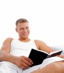 Man Reading Book In Bed Stock Photo