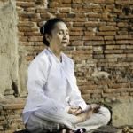 Woman Meditating Against Ancient Temple Stock Photo