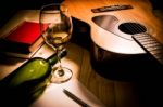 Guitar With Red Book And Wine On A Wooden Table Stock Photo