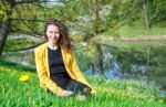 Young Woman Sitting On The Grass Near The Pond Stock Photo