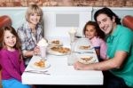 Cheerful Family Of Four Enjoying Dinner Stock Photo