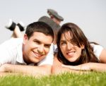 Happy Young Couple Lie Down On Grass Stock Photo