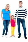 Sweet Little Kid Standing In Between Her Parents Stock Photo