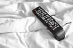 Remote On Bed Sheets Stock Photo