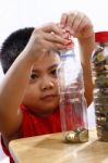 Little Boy Putting Money In A Bottle Stock Photo