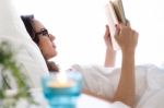 Beautiful Young Woman Reading A Book In The Bed Stock Photo