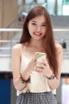 Portrait Of Thai Adult Beautiful Girl Using Her Smart Phone And Smile Stock Photo