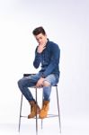 Male Model In Denim Jeans Sitting On A Chair . Studio Shoot Stock Photo