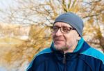 Elderly Man Wearing Glasses, A Gray Hat And Blue Jacket In A Cit Stock Photo