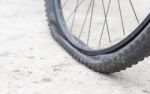 Bicycle Wheel With Flat Tyre On The Concrete Road Stock Photo