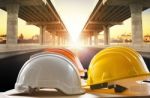 Safety Helmet On Civil Engineering Working Table Against Bridge Construction In Urban Scene Stock Photo