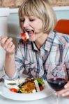 Woman Relishing Her Meal With Red Wine Stock Photo