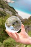 Hand Holding Crystal Ball Near Sea And Mountain Stock Photo