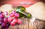 Bottle Of Red Wine, Grape And Corks On Wooden Table Stock Photo