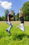 Young Dutch Couple Jumping In Green Meadow Stock Photo