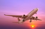 Commercial Airplane Flying At Sunset Stock Photo