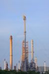 Fire Burning Over Oil Refinery Chimney Against Blue Sky Stock Photo