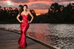 Beautiful Young Woman In The Gardens Wearing A Long Silk Red Dress Stock Photo