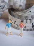 Miniature Woman Standing Near Measuring Tape, Thinking Of Weight Stock Photo