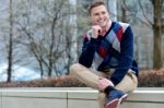 Stylish Young Man Sitting In Sidewalk Stock Photo