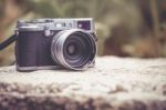 Vintage-style Digital Camera On Boulder Over Blurred Nature Backgrouna Stock Photo