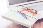 Notebook And Eyeglasses With Computer On Wooden Table Stock Photo