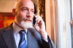 Middle-aged Businessman Listening On Smartphone At Home Stock Photo