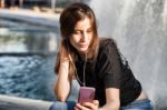 Young Woman Sitting  And Listening To Her  Music Stock Photo