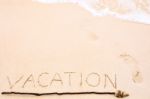 Inscription Of Vacation Written On Wet Yellow Beach Sand With Fo Stock Photo