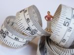 Miniature Woman Standing Near Measuring Tape, Thinking Of Weight Stock Photo