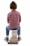 Back Pose Of Boy Sitting On Books Stock Photo