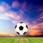 Soccer Ball With Soccer Field Against Beautiful Sunset Stock Photo