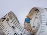 Miniature Woman Standing Near Measuring Tape, Thinking Of Weight Stock Photo