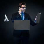 Stressed Businessman Talking On Phone Surrounded By Technology Stock Photo