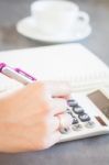 Hand Holding Pen And Pressing Calculator Buttons Stock Photo