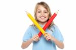 Young Girl Holding Big Red And Yellow Pencils Stock Photo