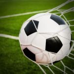 Soccer Football In Goal Net With Green Grass Field Stock Photo