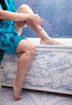 Woman Shaving Leg Sitting In The Bathroom Stock Photo