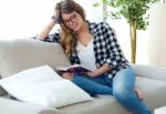 Beautiful Young Woman Reading A Book In The Sofa Stock Photo