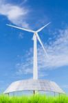 Solar Panels And Wind Turbine On Green Grass Field Against Blue Stock Photo