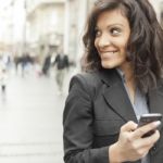 Young Woman With Smartphone Walking On Street Stock Photo