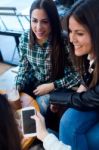 Three Young Woman Using Mobile Phone At Cafe Shop Stock Photo